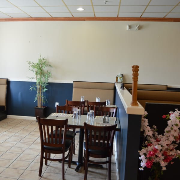 Dining area at Pepper House Township with set tables, booth seating, and a decorative plant.
