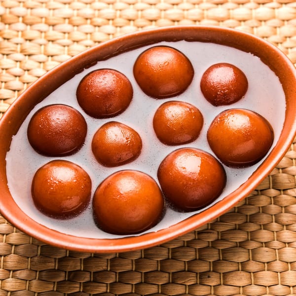 A terracotta bowl filled with Gulab Jamun, Indian fried dough balls soaked in sweet syrup.